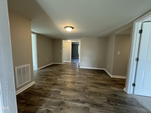 empty room with visible vents, baseboards, and dark wood-style floors