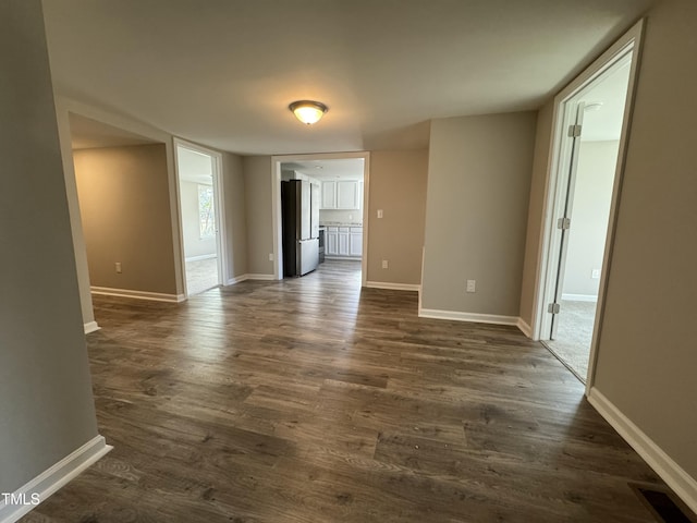 unfurnished room with visible vents, dark wood-type flooring, and baseboards