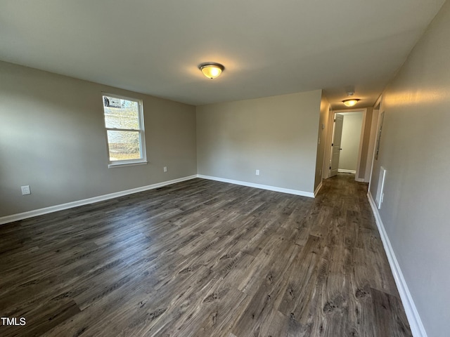 unfurnished room featuring dark wood-type flooring and baseboards