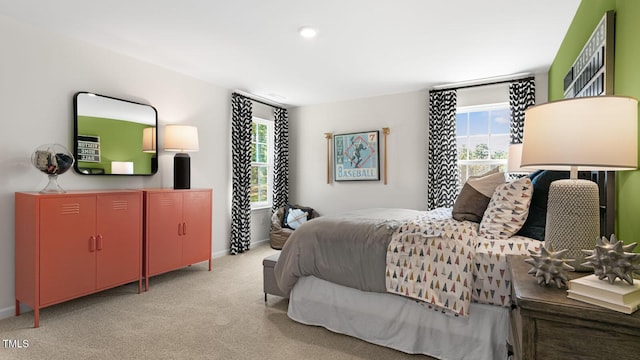 bedroom with light carpet, multiple windows, and baseboards