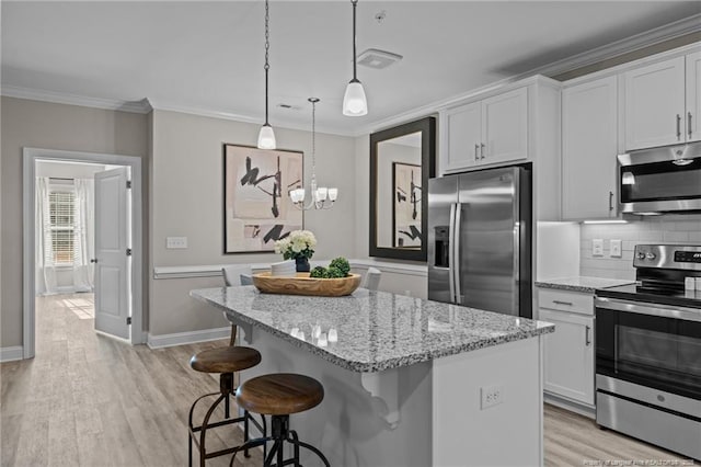 kitchen featuring a center island, stainless steel appliances, tasteful backsplash, light wood-style flooring, and ornamental molding