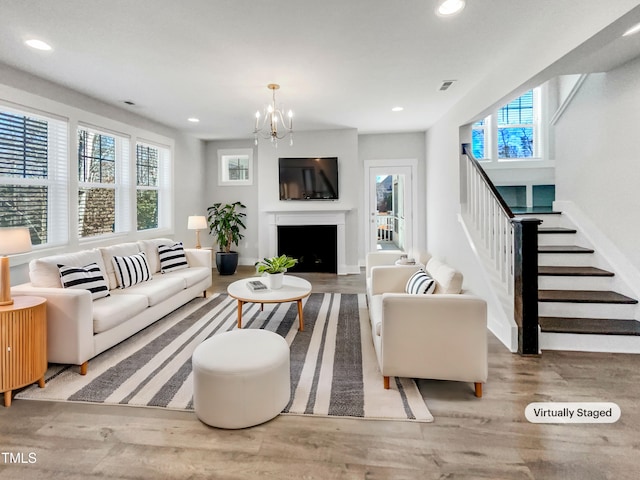 living area with a fireplace, recessed lighting, visible vents, wood finished floors, and stairs