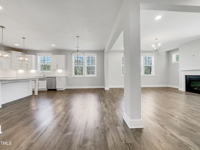 unfurnished living room with an inviting chandelier, a fireplace, and dark wood finished floors