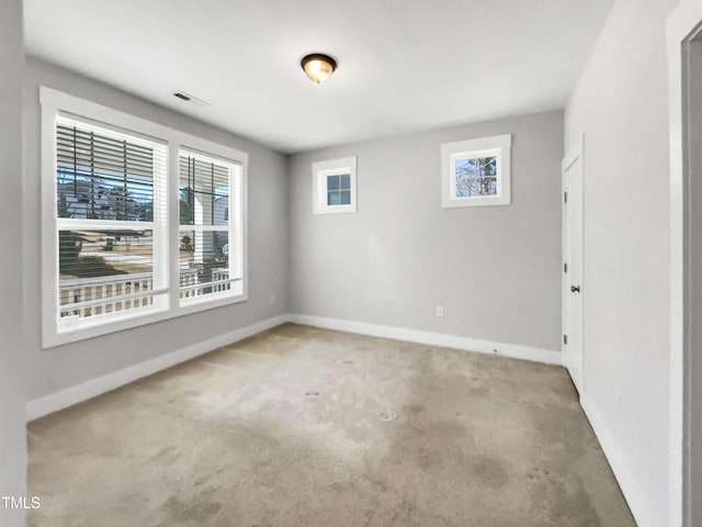 spare room with baseboards, a healthy amount of sunlight, visible vents, and carpet flooring