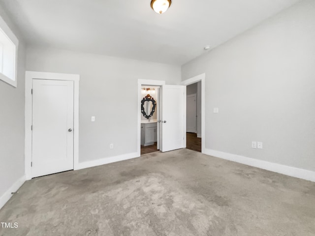 unfurnished bedroom featuring carpet floors, ensuite bath, and baseboards