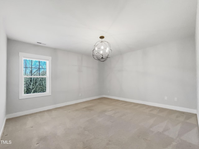 spare room with carpet, a notable chandelier, and baseboards