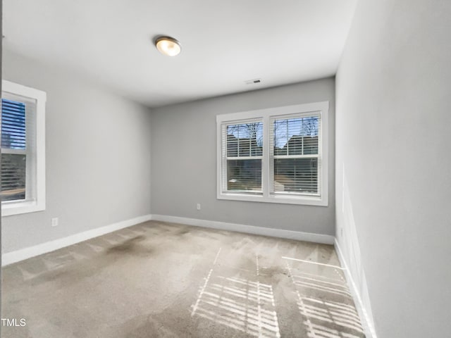 carpeted empty room with visible vents and baseboards