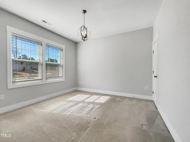 spare room featuring carpet, a notable chandelier, and baseboards