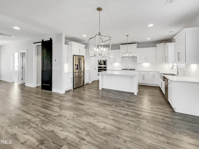 kitchen featuring white cabinetry, recessed lighting, a barn door, a kitchen island, and stainless steel appliances