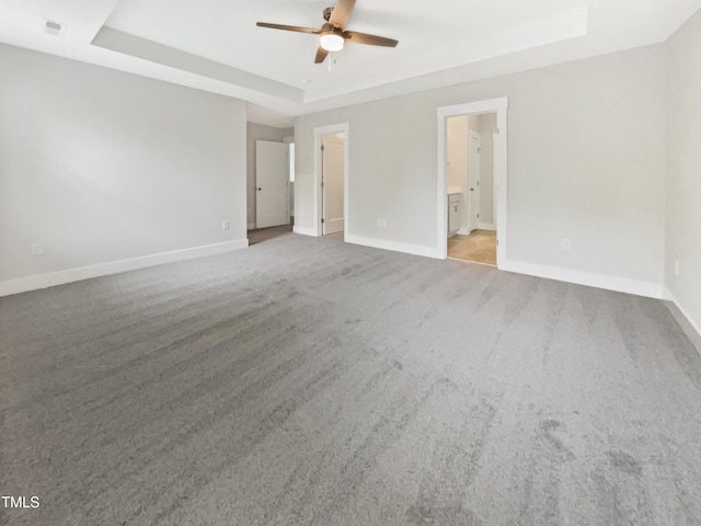 unfurnished bedroom with connected bathroom, a ceiling fan, light carpet, a raised ceiling, and baseboards