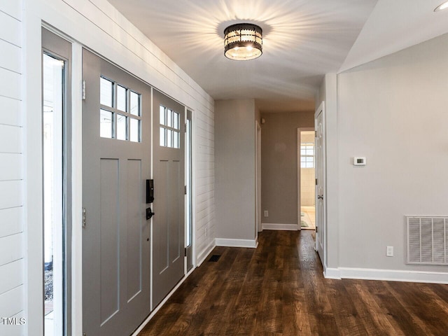 foyer entrance with dark wood finished floors, visible vents, and baseboards