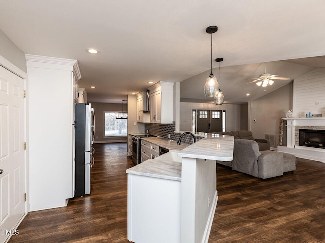 kitchen featuring appliances with stainless steel finishes, open floor plan, white cabinets, and dark wood finished floors