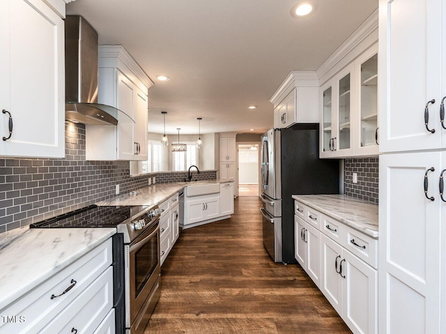 kitchen featuring wall chimney exhaust hood, appliances with stainless steel finishes, white cabinets, and a sink