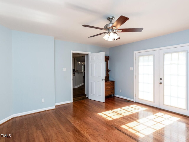 empty room with ceiling fan, french doors, wood finished floors, and baseboards