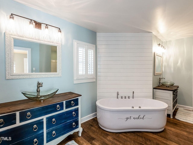 full bathroom with a soaking tub, wood finished floors, vanity, and baseboards