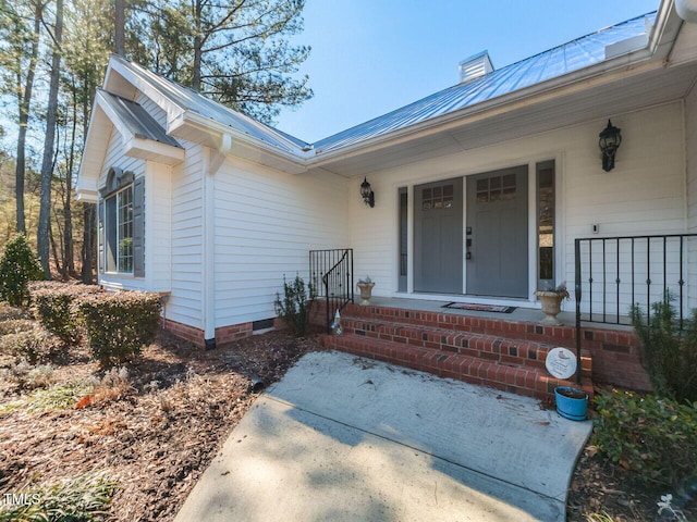 entrance to property with crawl space, covered porch, metal roof, and a chimney