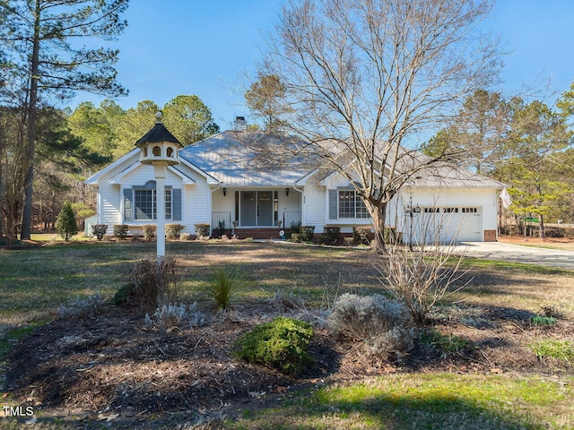 view of front of property featuring a chimney, a porch, a garage, driveway, and a front lawn