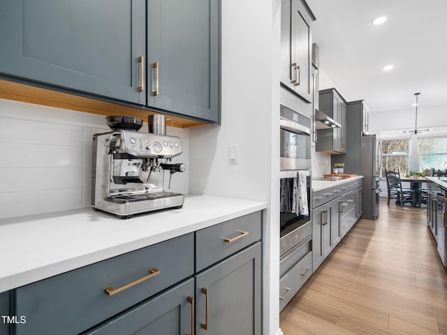 kitchen with recessed lighting, light countertops, backsplash, light wood-style flooring, and appliances with stainless steel finishes