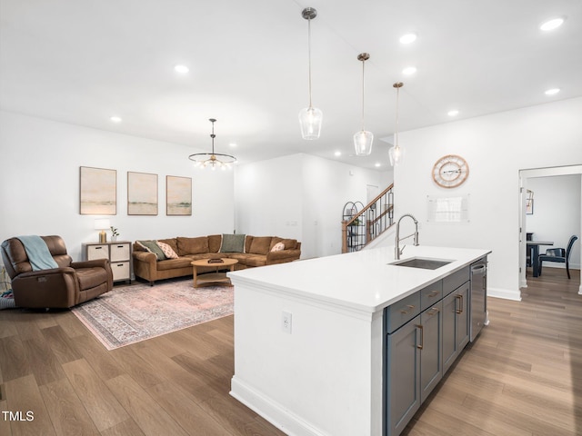 kitchen featuring gray cabinetry, a sink, light wood-style flooring, and stainless steel dishwasher