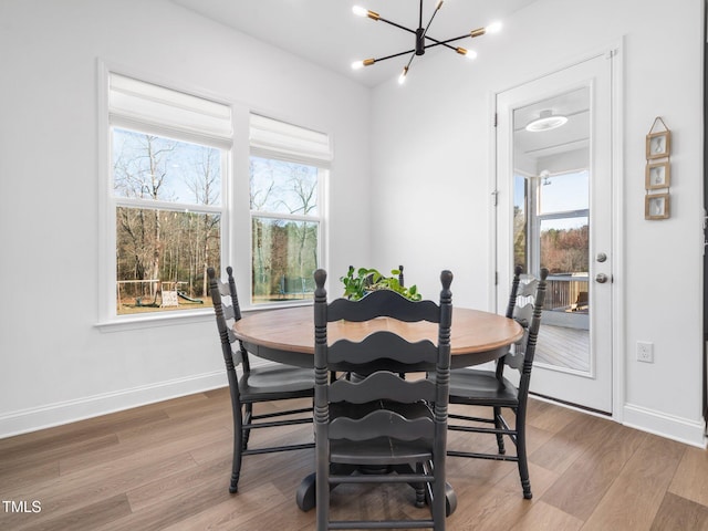 dining space with wood finished floors, a wealth of natural light, and a notable chandelier