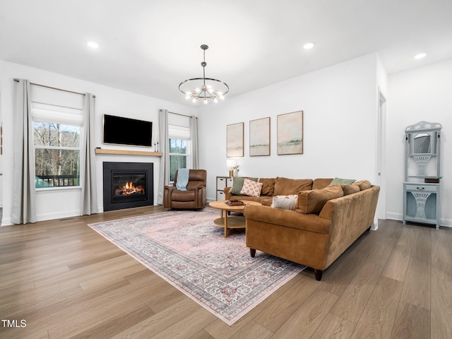 living room with light wood-type flooring, recessed lighting, a wealth of natural light, and a glass covered fireplace