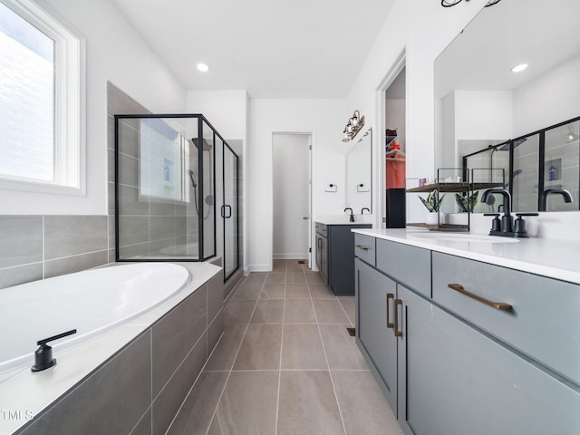 full bath with a stall shower, two vanities, a sink, tile patterned flooring, and a bath