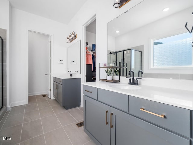 bathroom with tile patterned flooring, two vanities, a sink, a spacious closet, and a stall shower