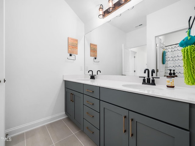 bathroom featuring double vanity, a sink, baseboards, and tile patterned floors