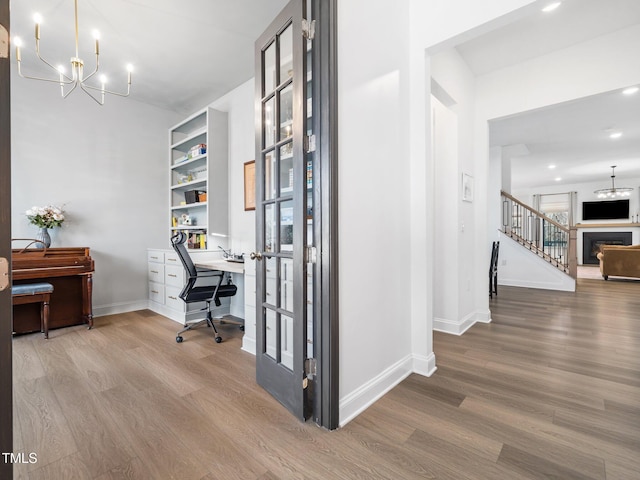 home office featuring recessed lighting, a fireplace, wood finished floors, baseboards, and an inviting chandelier