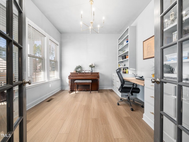 office area featuring light wood finished floors, baseboards, visible vents, and an inviting chandelier