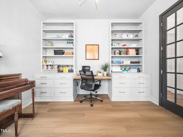 home office with built in features, light wood-type flooring, built in study area, and baseboards