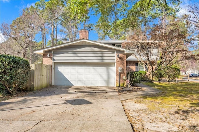 traditional-style home featuring a garage, brick siding, fence, concrete driveway, and a chimney