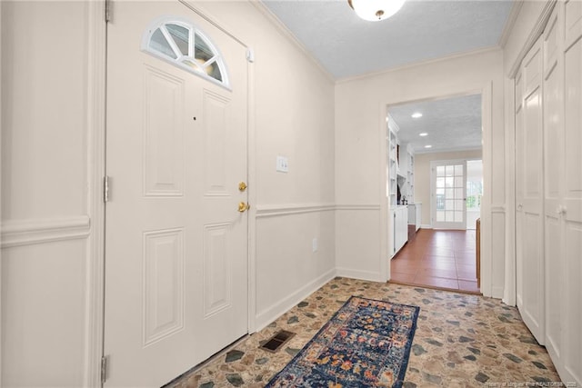 foyer with a textured ceiling, visible vents, crown molding, and recessed lighting