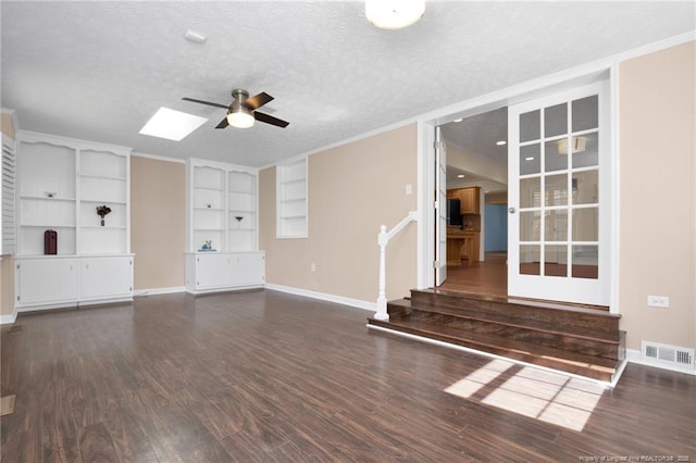 unfurnished living room featuring a textured ceiling, wood finished floors, stairs, and visible vents