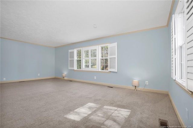 spare room with ornamental molding, visible vents, carpet floors, and baseboards