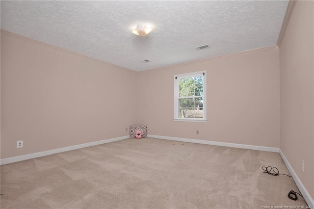 spare room with a textured ceiling, visible vents, baseboards, ornamental molding, and carpet