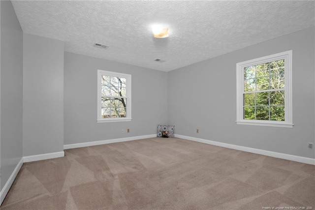 spare room with baseboards, carpet flooring, visible vents, and a healthy amount of sunlight