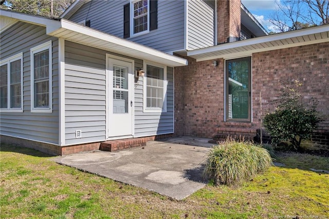 entrance to property featuring a patio area and a lawn