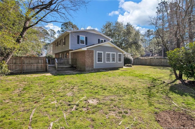 back of property with brick siding, a fenced backyard, and a yard