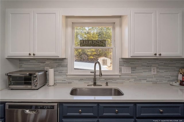 kitchen featuring a toaster, dishwasher, light countertops, white cabinetry, and a sink