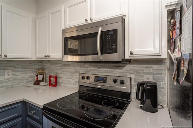 kitchen with white cabinets, appliances with stainless steel finishes, light countertops, and backsplash