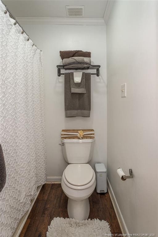 bathroom with toilet, crown molding, visible vents, and wood finished floors