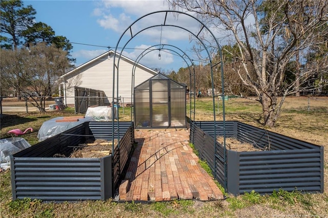 view of yard featuring a garden, fence, a greenhouse, and an outbuilding