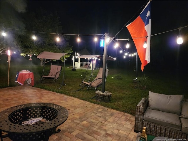 patio at night with a yard and a fire pit