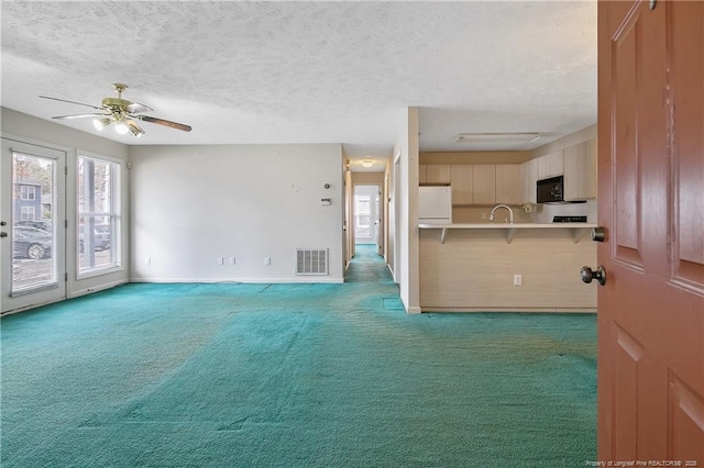 interior space featuring black microwave, light colored carpet, visible vents, light countertops, and freestanding refrigerator