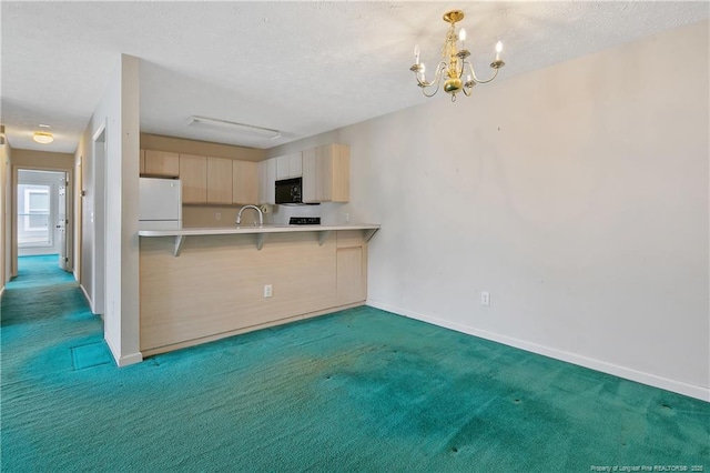 kitchen with black microwave, carpet floors, light countertops, freestanding refrigerator, and a kitchen bar