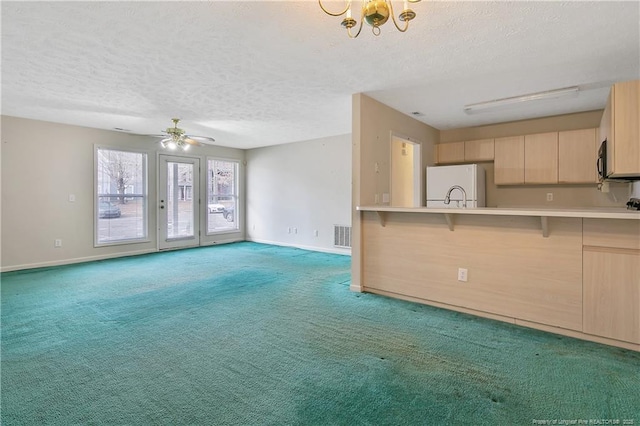 kitchen with light colored carpet, a textured ceiling, fridge, light brown cabinets, and black microwave