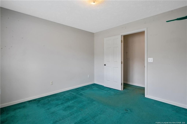 carpeted empty room with a textured ceiling and baseboards