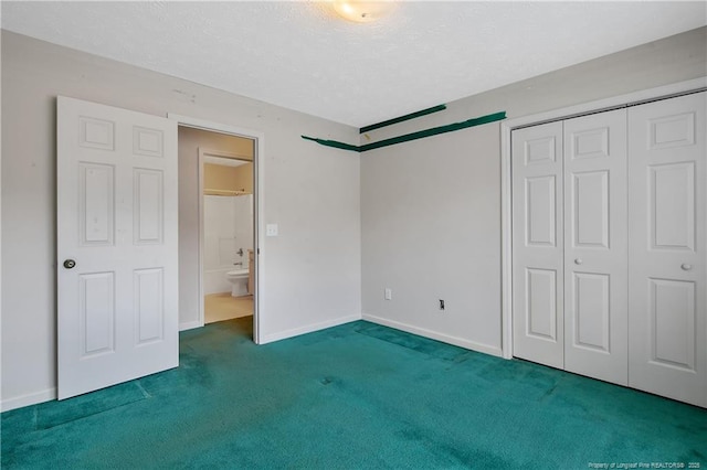 unfurnished bedroom with carpet, a closet, a textured ceiling, and baseboards