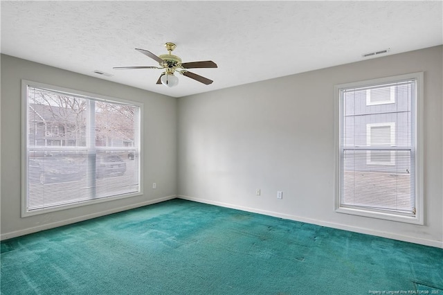 carpeted spare room with a textured ceiling, baseboards, visible vents, and a ceiling fan